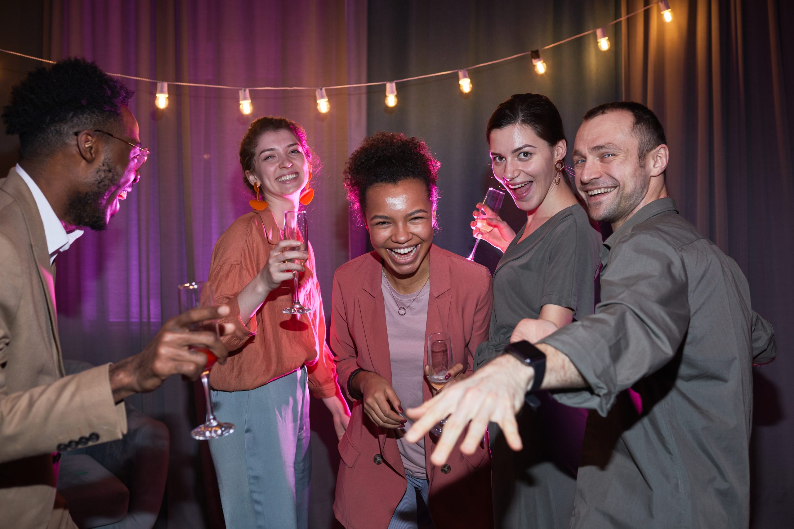 Diverse group of carefree people dancing while enjoying party at home, shot with flash